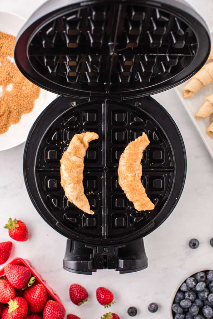 Preheat your waffle iron and place two crescent rolls onto the waffle iron.