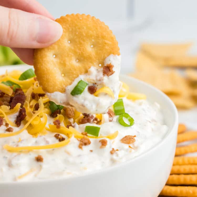 Crack dip in serving bowl with topped with fixings and crackers for dipping