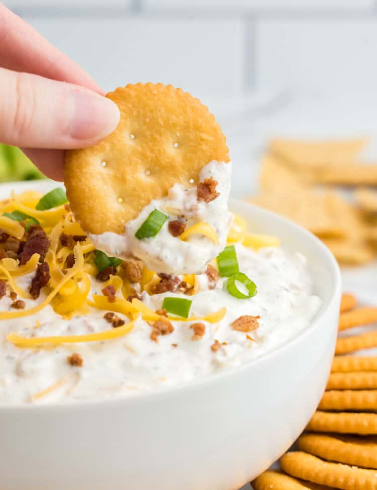 Crack dip in serving bowl with topped with fixings and crackers for dipping