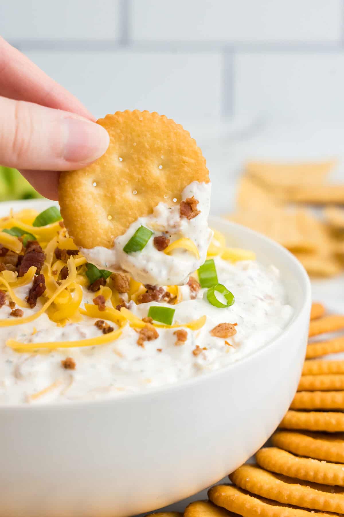 Crack dip in serving bowl with topped with fixings and crackers for dipping