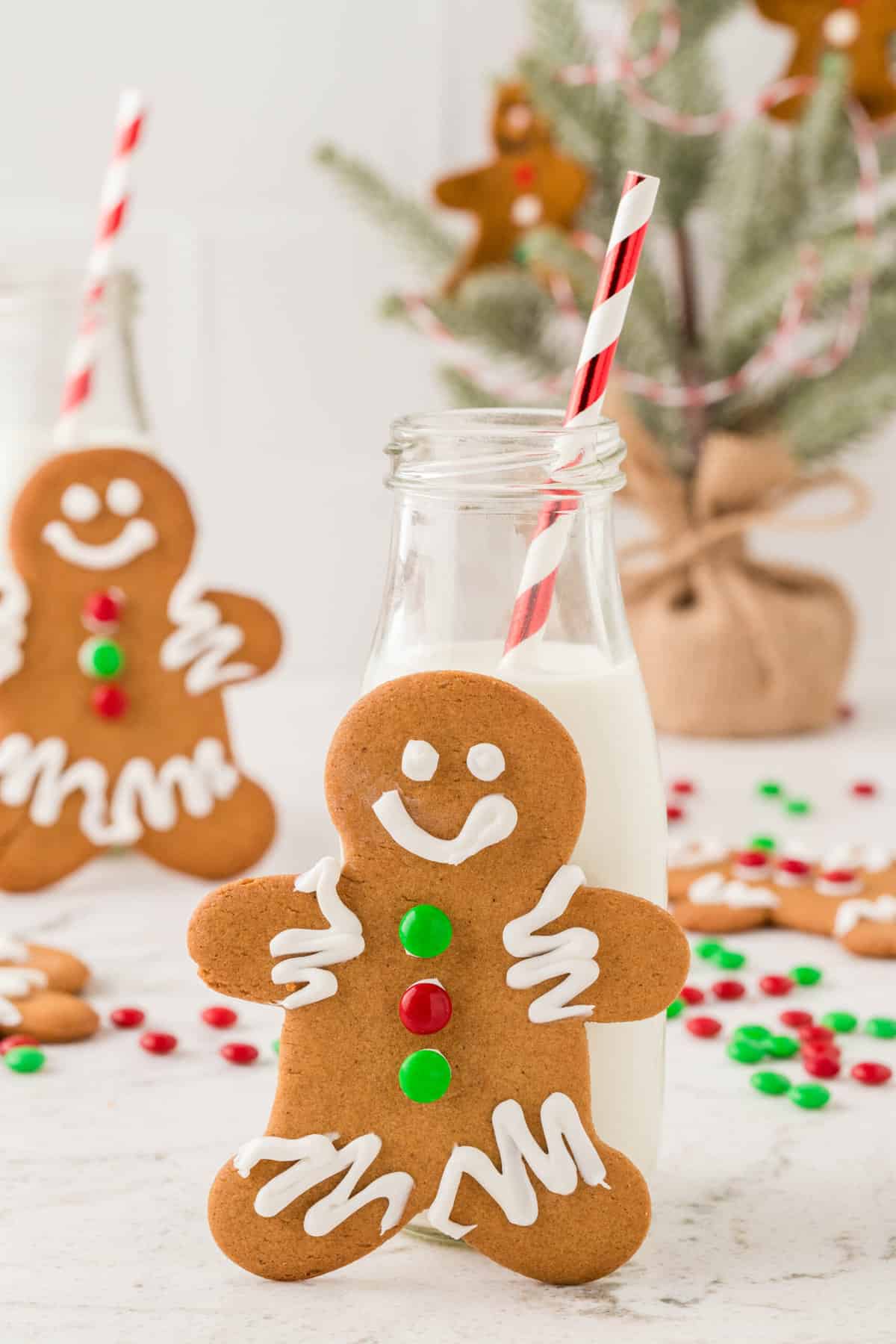 Close up photo of Completed gingerbread cookie on its feet leaning against a bottle of milk.