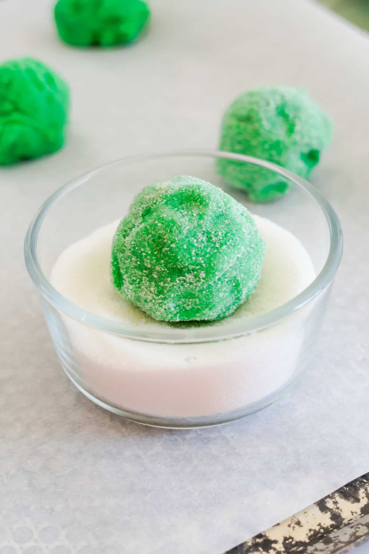 Gently roll dough balls in sugar and place them onto the baking sheet.