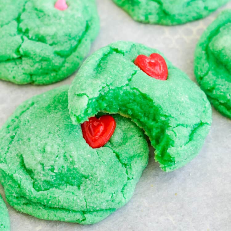 Cookies on parchment paper with one having a bite taken out of it to show how chewy and soft the cookies are.