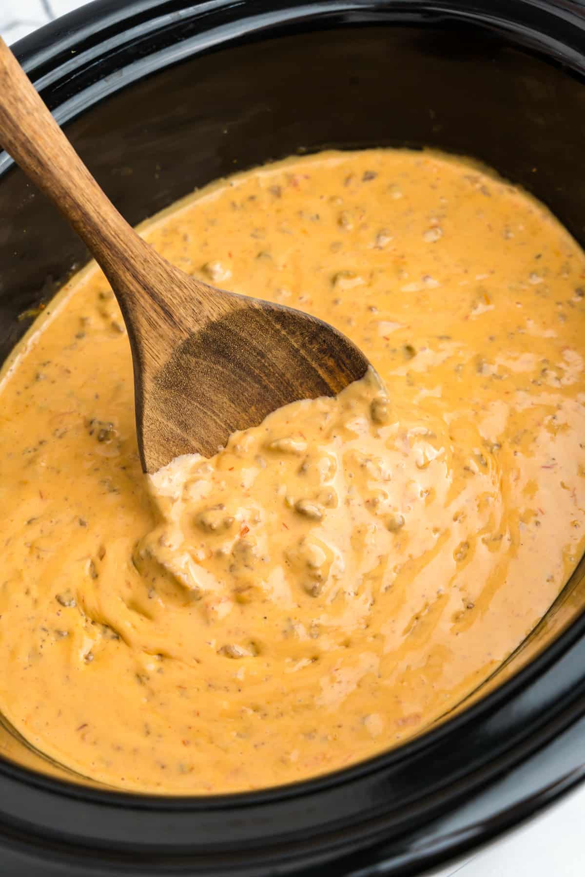 Using wooden spoon to stir Crock Pot Hamburger Dip