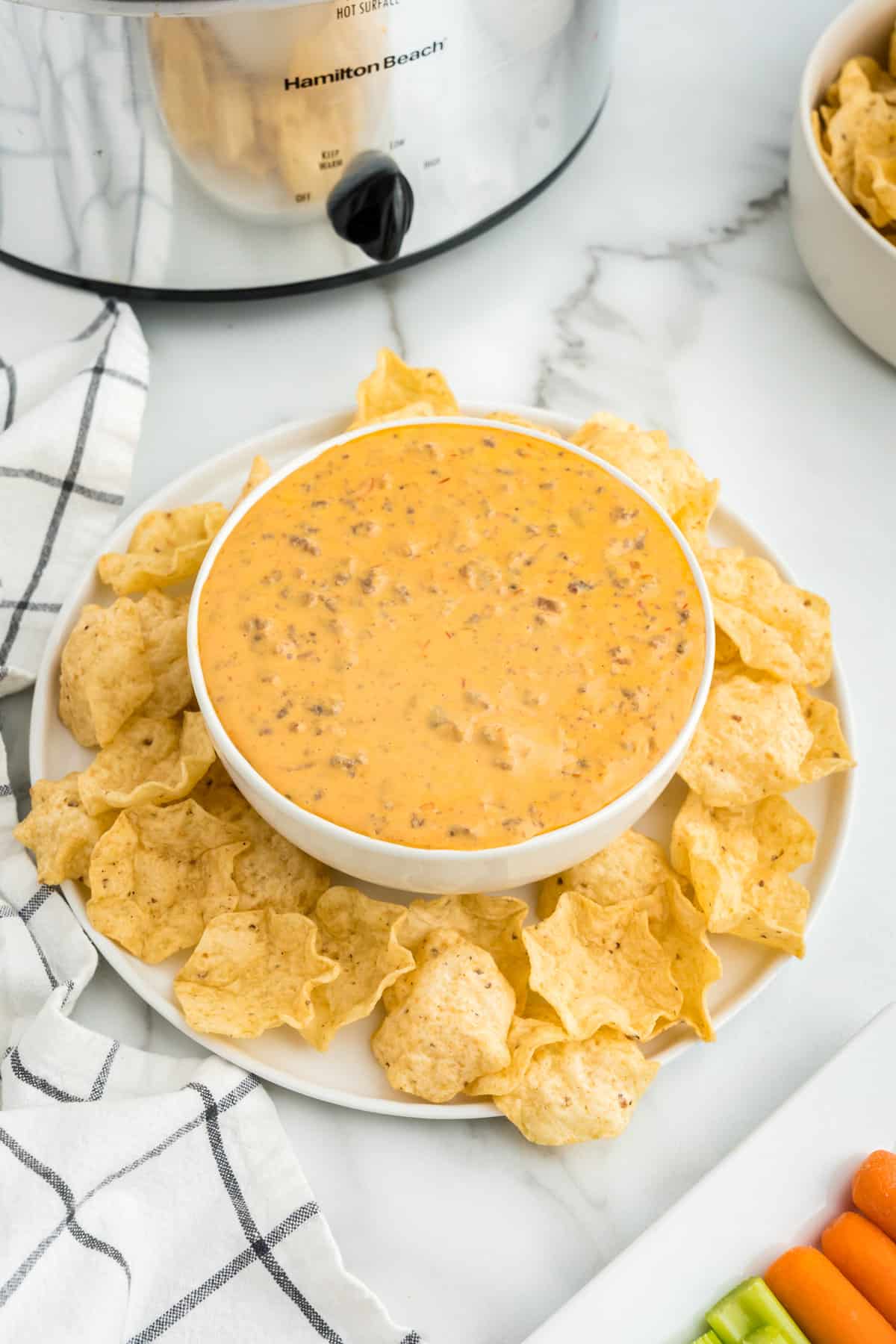 Crock Pot Hamburger Dip in serving bowl surrounded by tortilla chips on plate