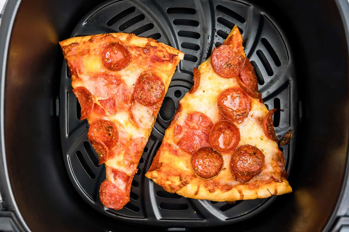 Two pizza slices in air fryer for Reheat Pizza in Air Fryer recipe