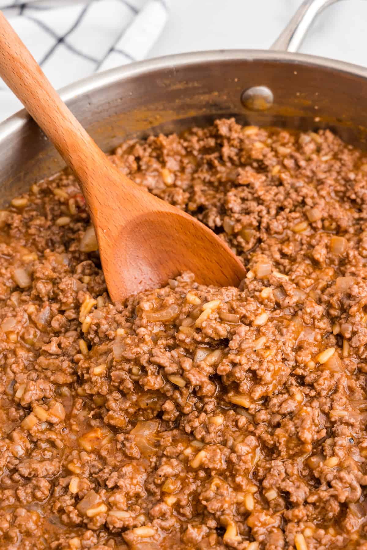 Mixing Large Batch Sloppy Joes in a skillet with a wooden sppon