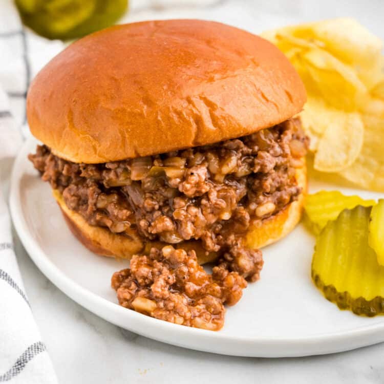 Close up image of Large Batch Sloppy Joes on plate with pickles and potato chips
