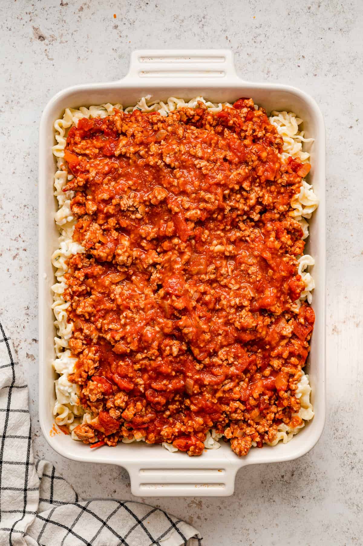 Adding the meat sauce atop noodles and cheese mixture for Lasagna Casserole