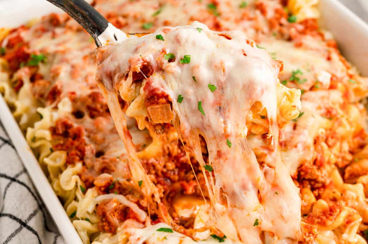 Lasagna Casserole being scooped from baking dish oozing with cheese