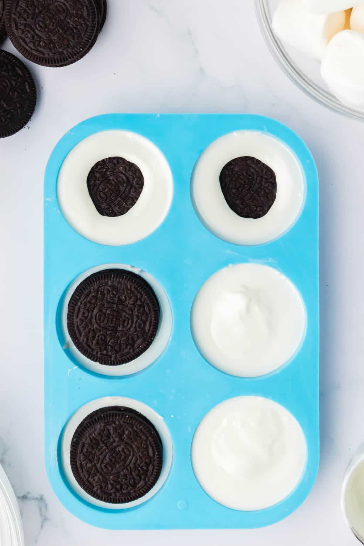 Place the Silicone Cookie Mold on a Flat Surface and fill 1/4 full of melted Chocolate. Place an Oreo in the Chocolate and Cover Completely. Use a Spoon if needed.