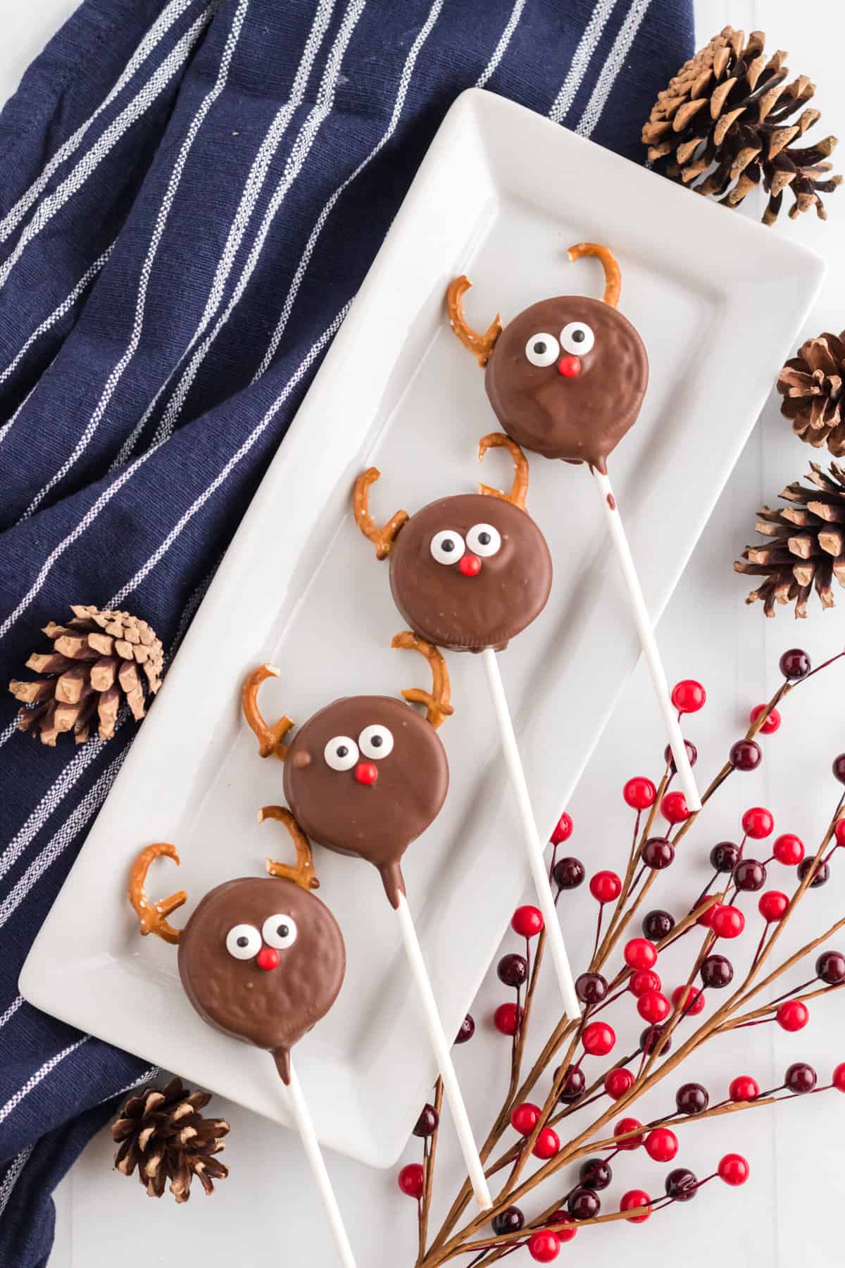 4 Oreo Cookies displayed on a rectangular white plate with acorns and Christmas decor laying around the plate.