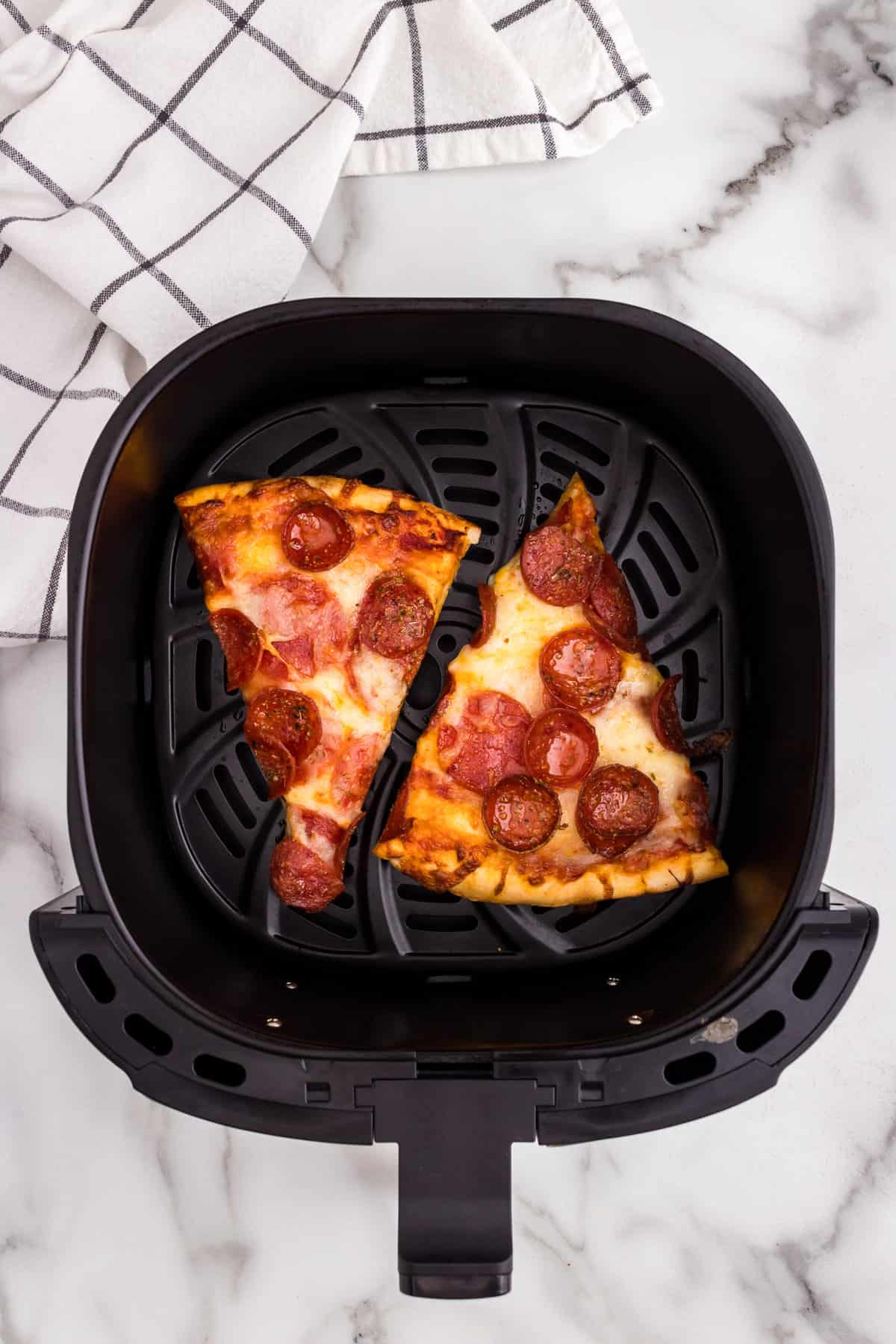 Two pepperoni pizza slices in air frly ero Reheat Pizza in Air Fryer recipe