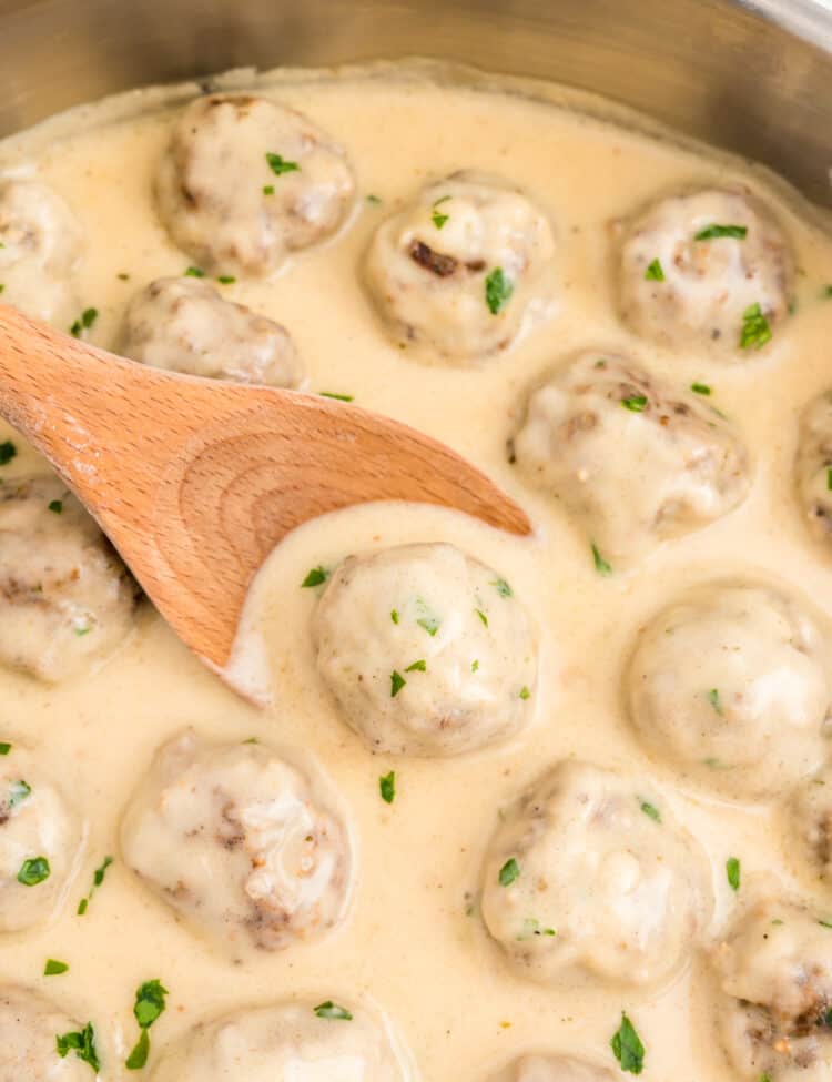 Wooden spoon scooping swedish meatball out of skillet