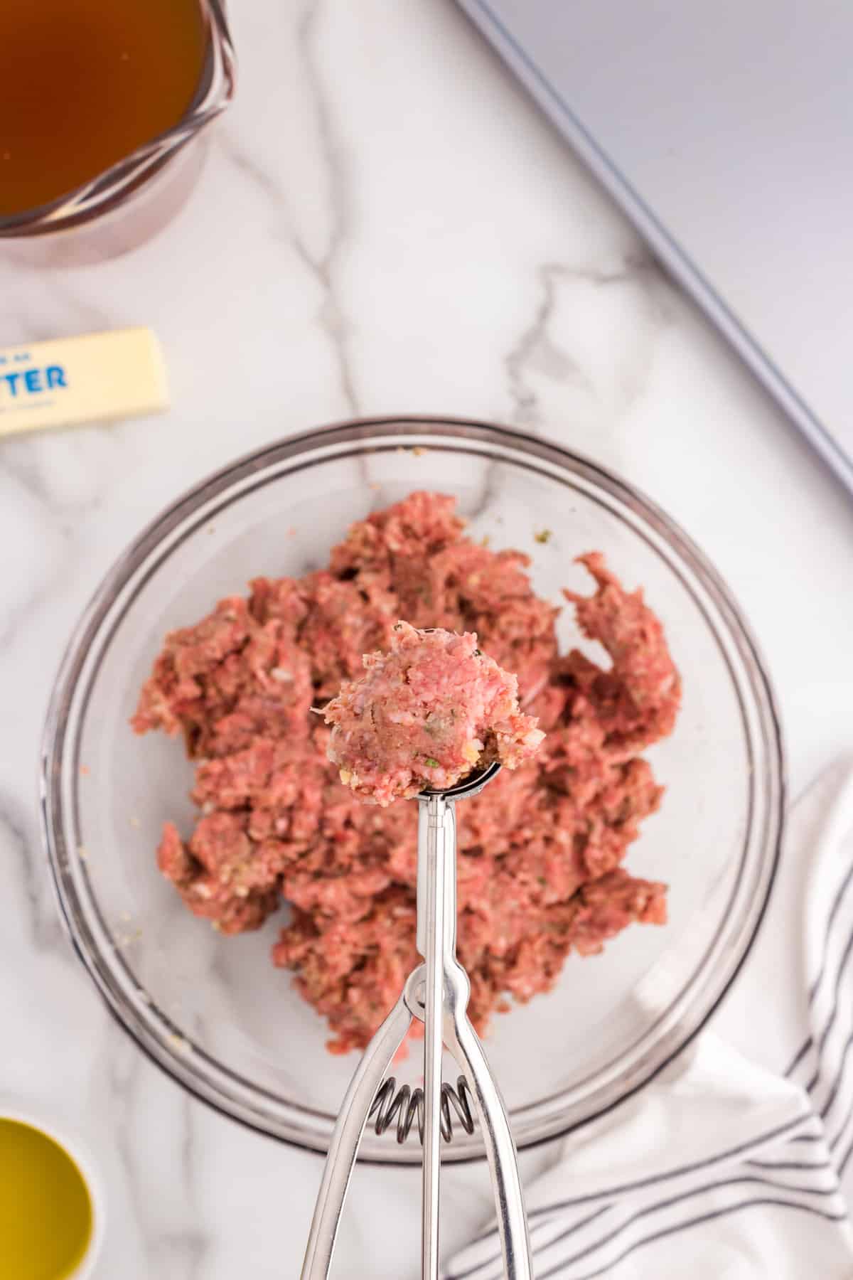 Cookie scoop with meatball mixture in it