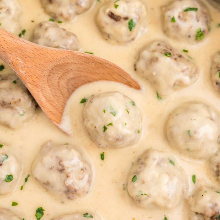 Swedish Meatballs in stovetop skillet being stirred with a wooden spoon