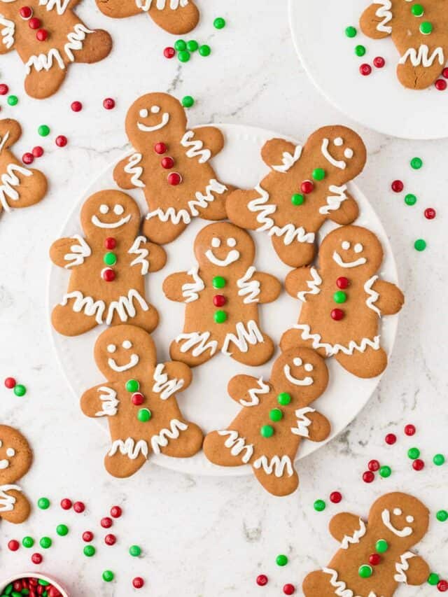 Gingerbread Cookies displayed on a white plate with Cookies laying on the table around around the plate.
