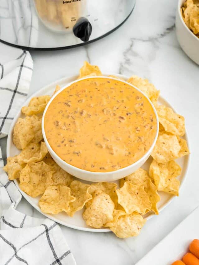 Crock Pot Hamburger Dip in serving bowl surrounded by tortilla chips on plate
