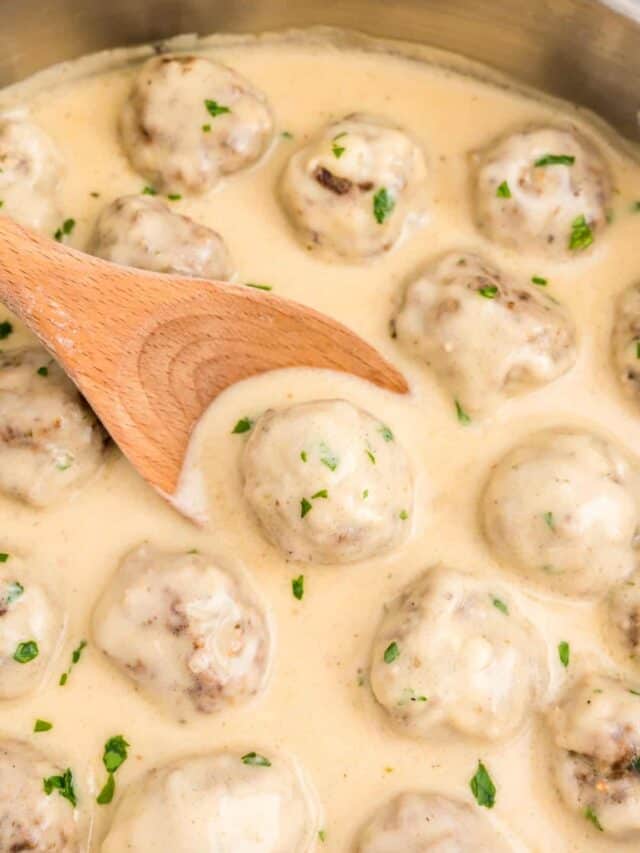 Wooden spoon scooping swedish meatball out of skillet