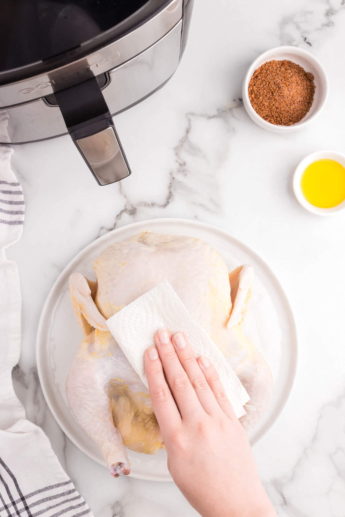 Patting chicken dry on plate before putting in the air fryer for Air Fryer Rotisserie Chicken
