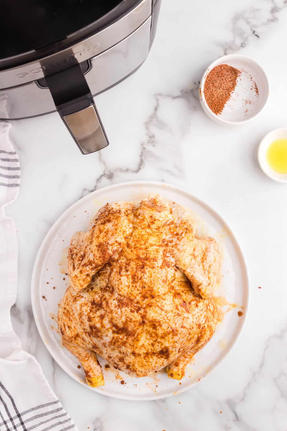 Coating the other side of the whole chicken with olive oil and BBQ Rub for Air Fryer Whole Chicken