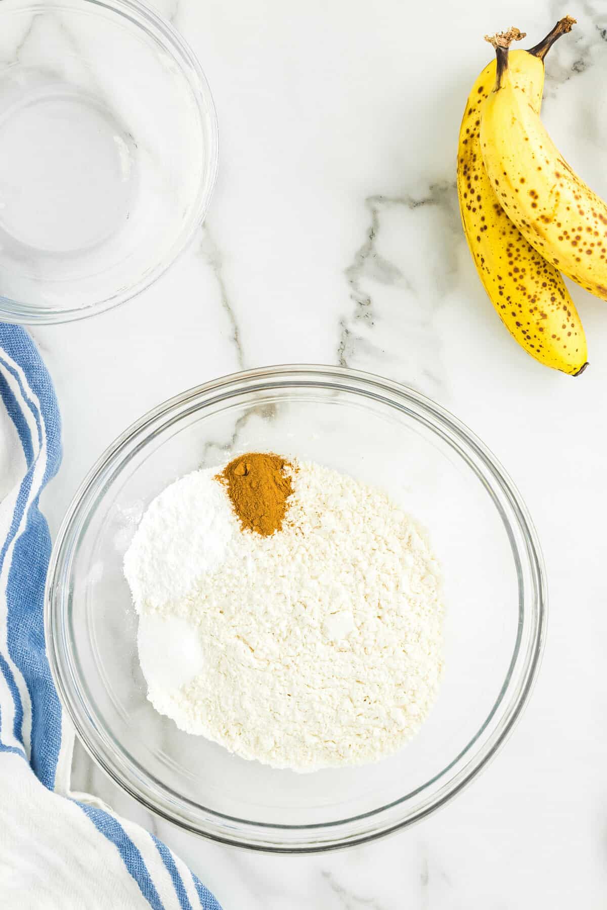 Combining Dry Ingredients for Banana Pancakes in Clear Mixing Bowl