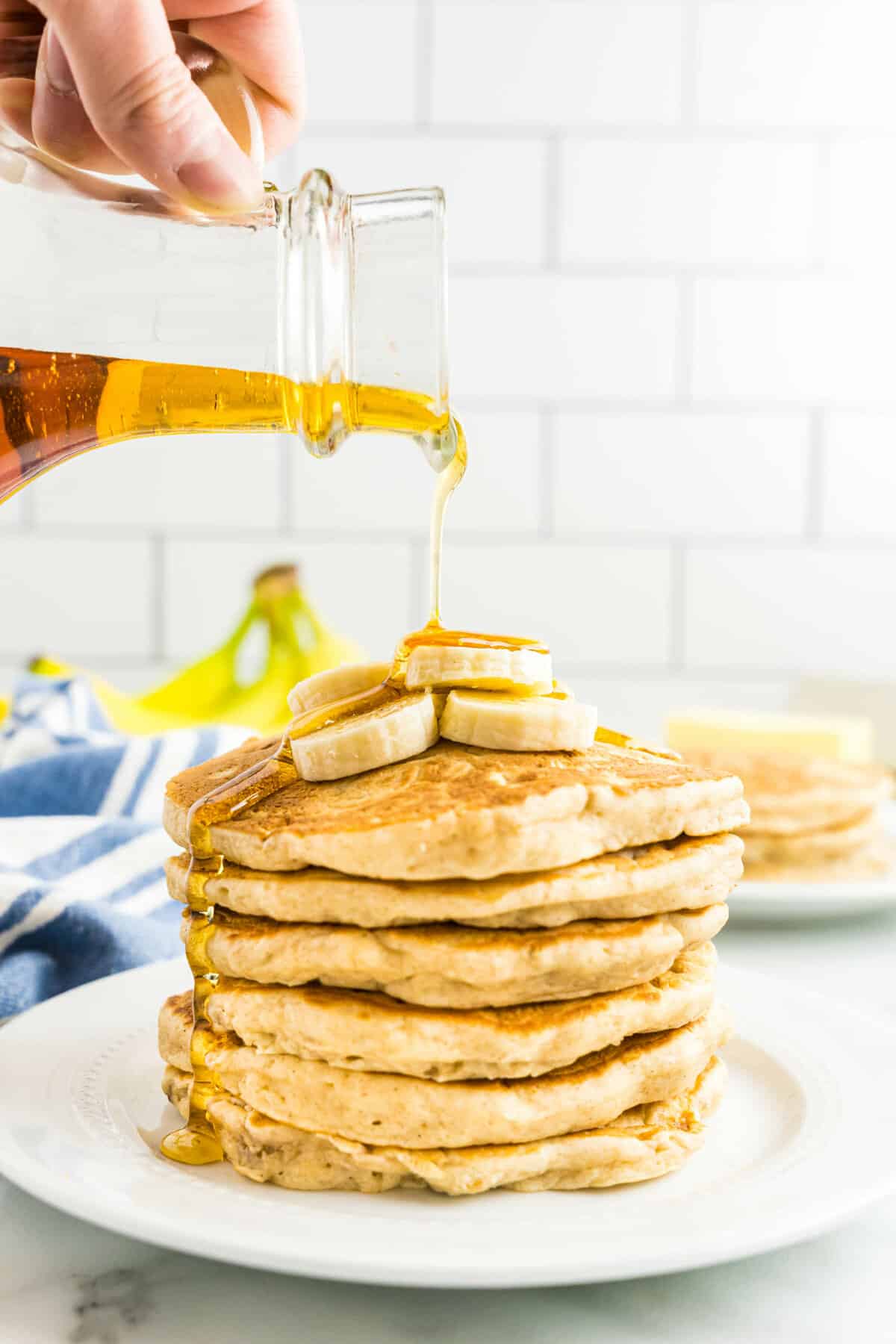 Pouring syrup on stack of banana pancakes