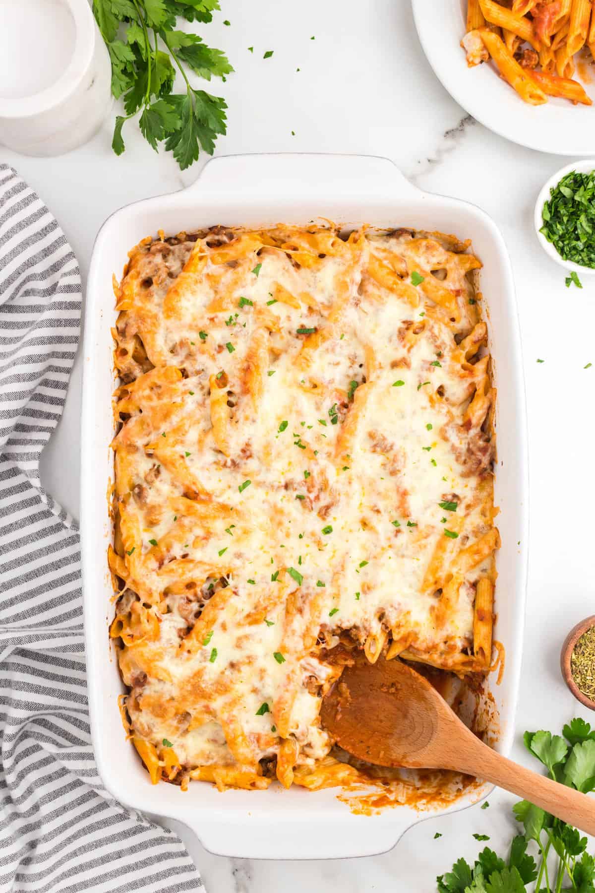 Using wooden spoon to scoop the first bite out of Ground Beef Casserole in baking dish