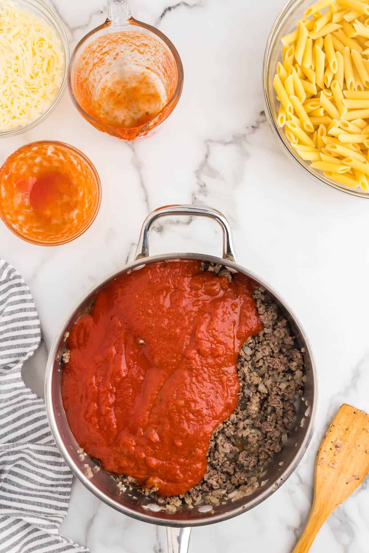 Adding marinara and tomato sauces to ground beef mixture in skillet for Ground Beef Casserole recipe