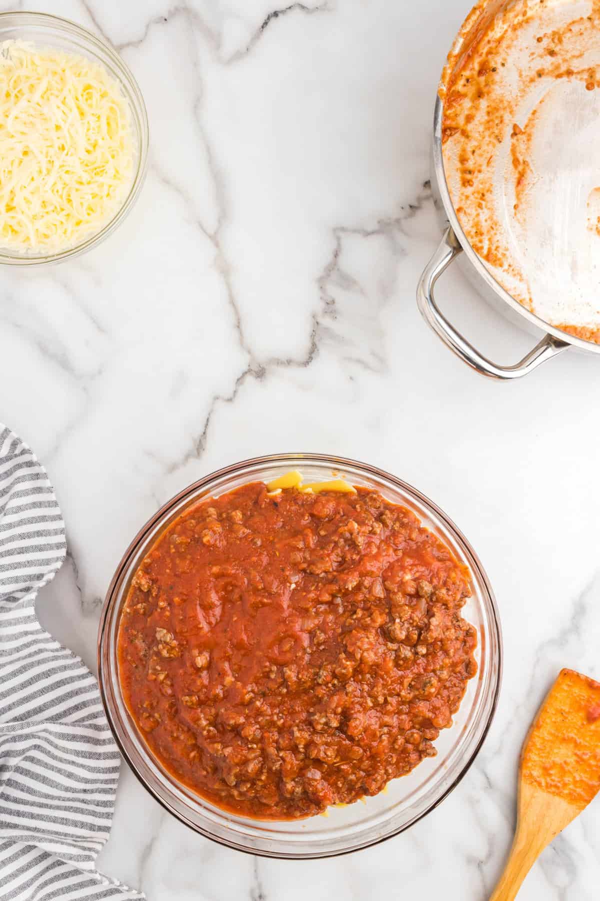 Adding ground beef mixture and cooked penne noodles in glass mixing bowl for Ground Beef Casserole