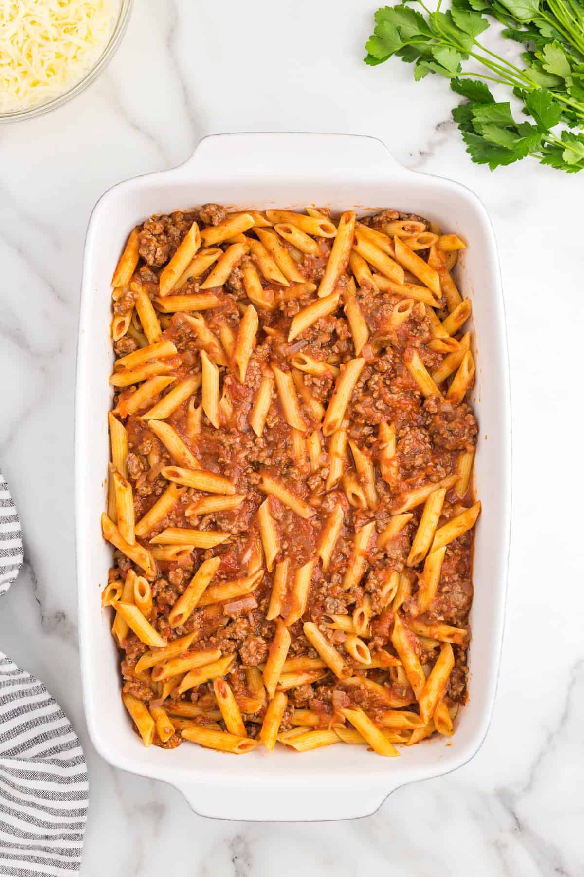Ground beef and noodle combined mixture in 9x13 baking dish for Ground Beef Casserole