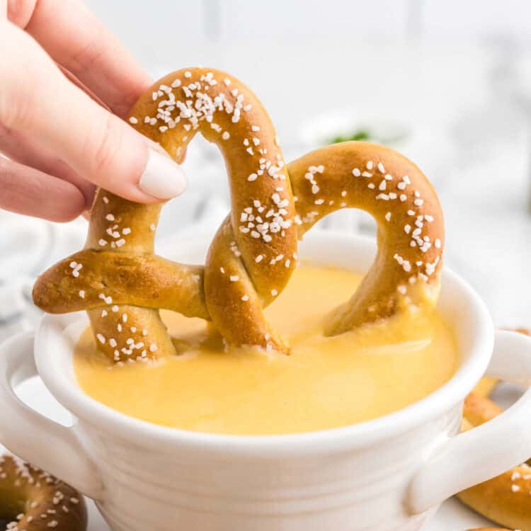Beer Cheese Dip in bowl using homemade pretzel to dip