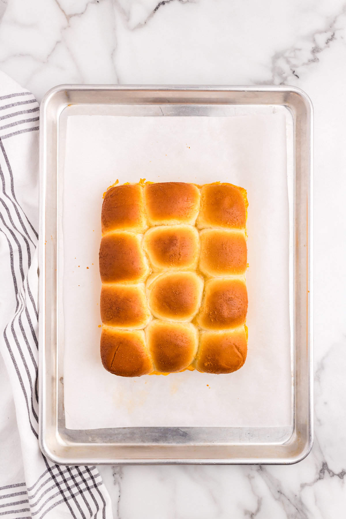 Buffalo Chicken Sliders baked to a golden brown on parchment paper lined baking sheet