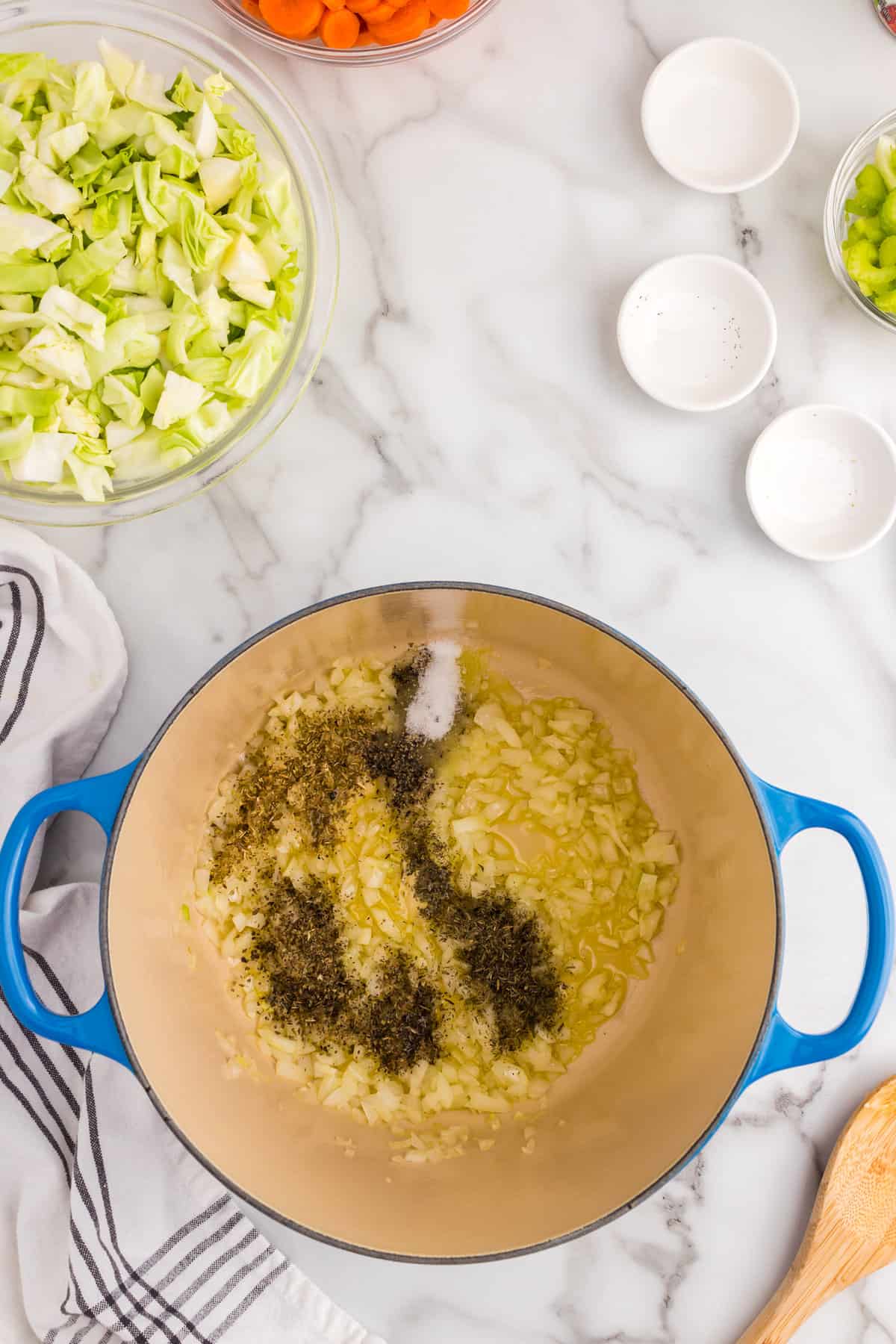 Adding seasonsing to Cabbage Vegetable Soup mixture in Dutch Oven