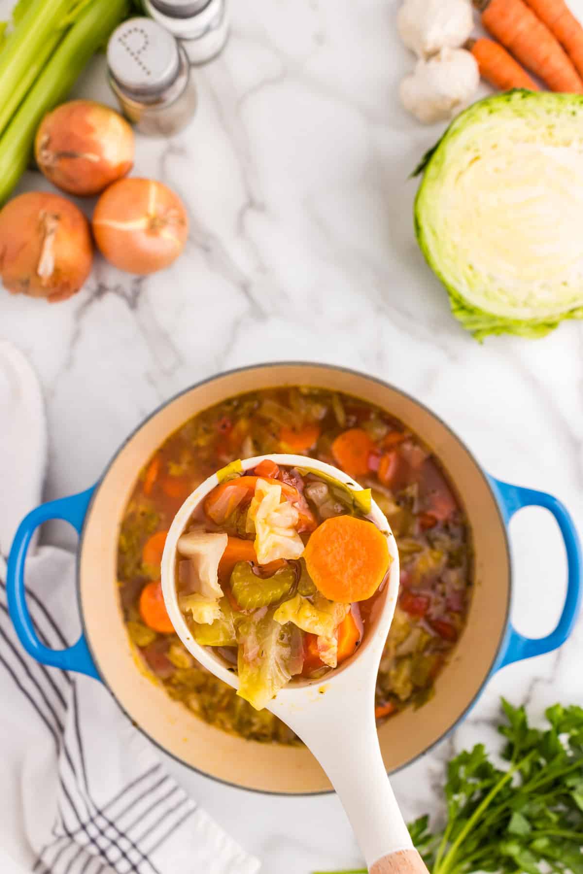 Using spoon to scoop Cabbage Vegetable Soup from Dutch Oven