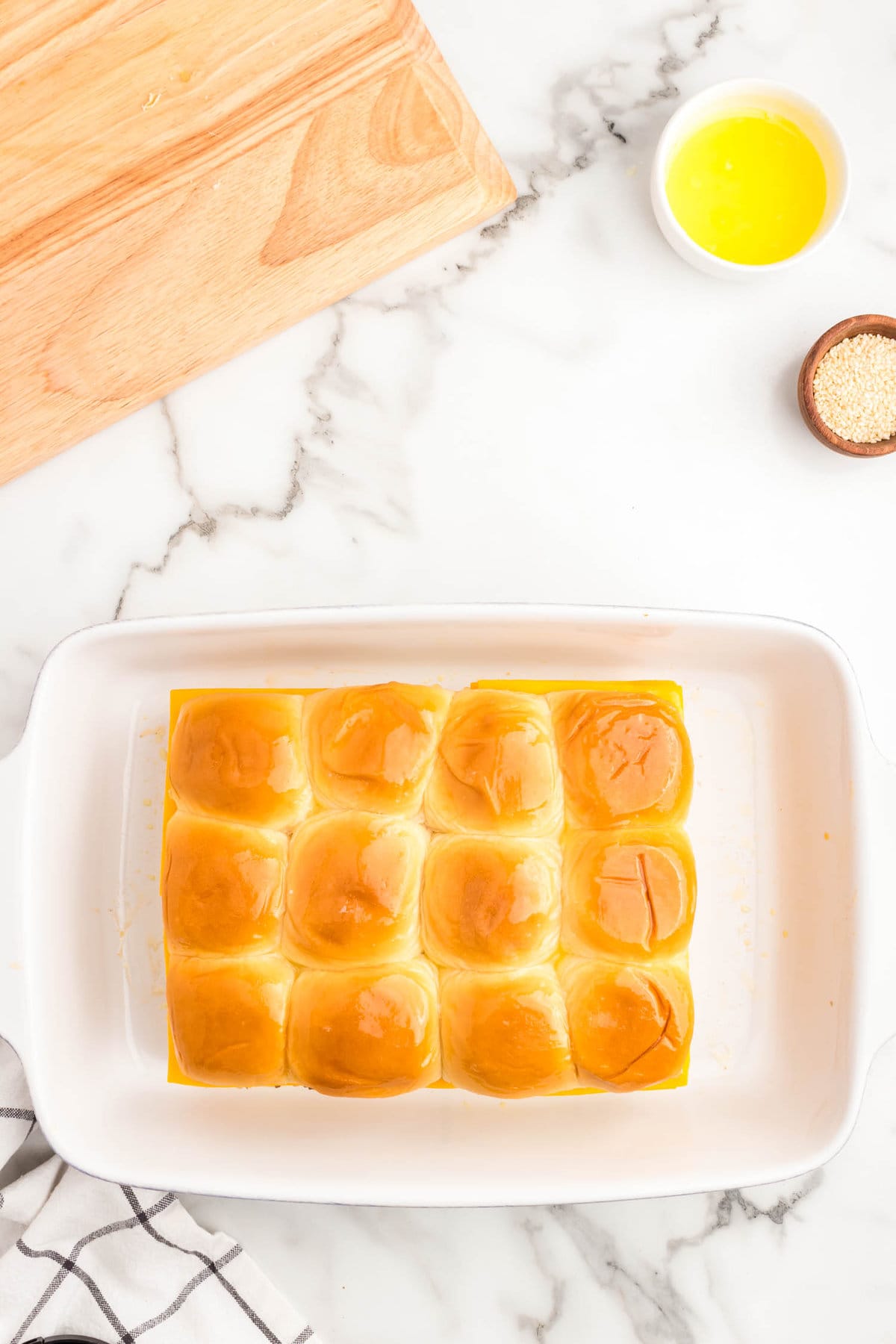 Covering the layers with the top half of the hawaiian sweet rolls for Cheeseburger Sliders