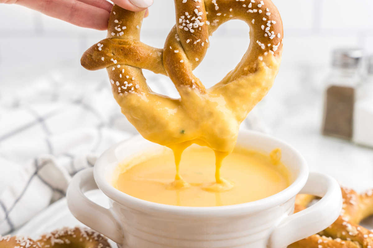 Beer Cheese Dip in serving bowl using homemade pretzel to dip 
