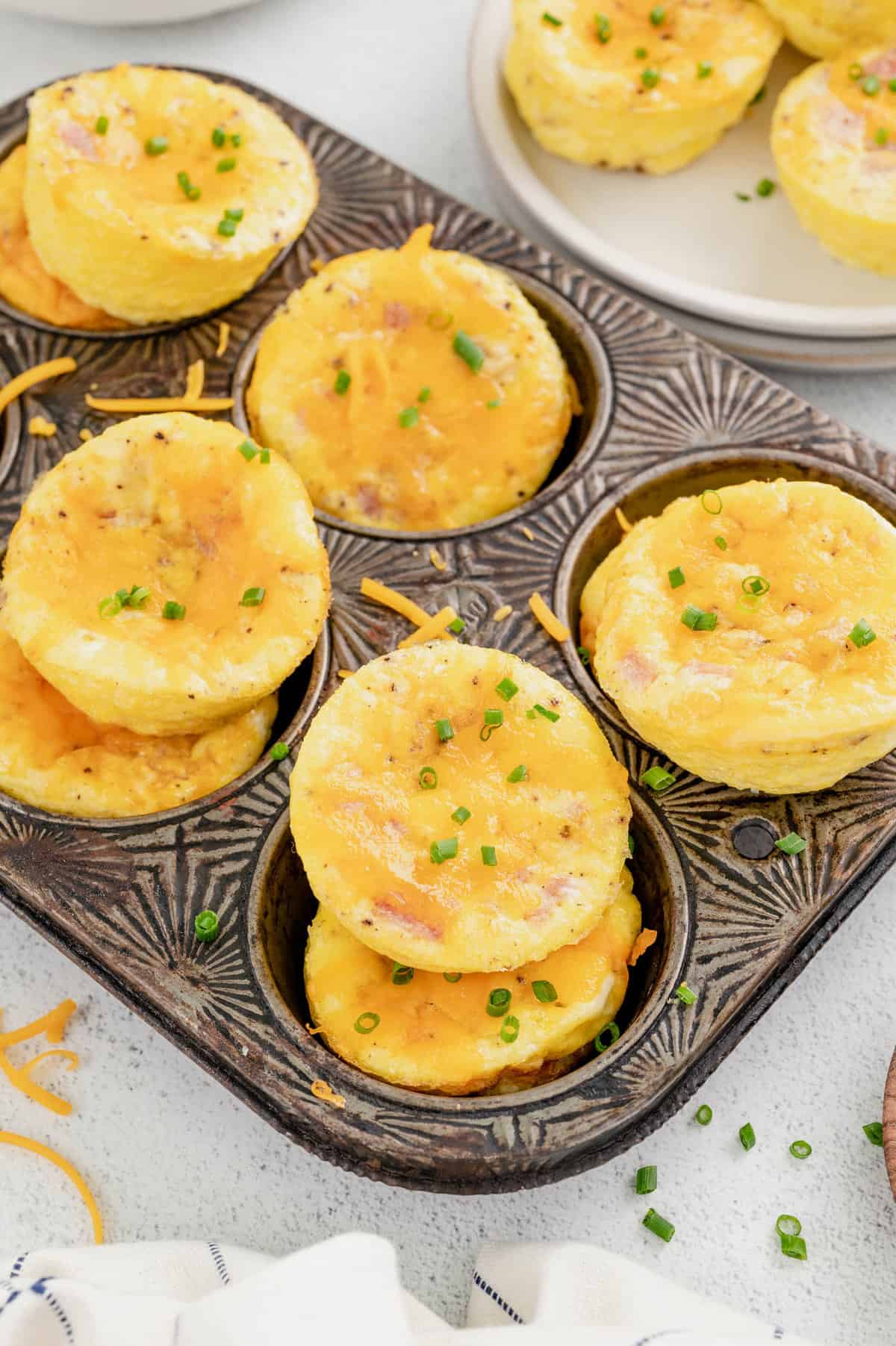 Egg Muffin Cups stacked in muffin tin topped with chives