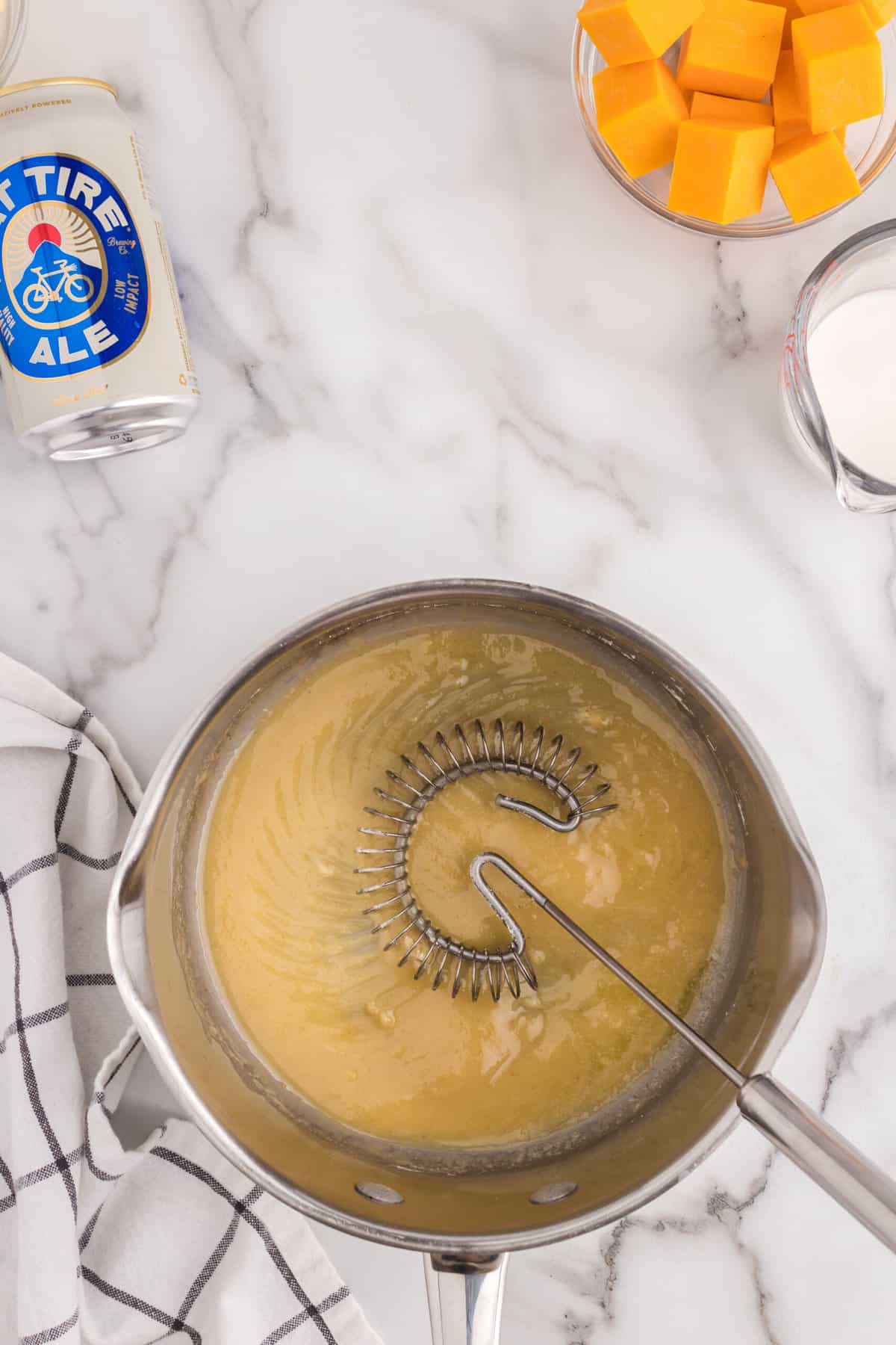 Slowly whisking in flour to Beer Cheese Dip recipe in medium sauce pan