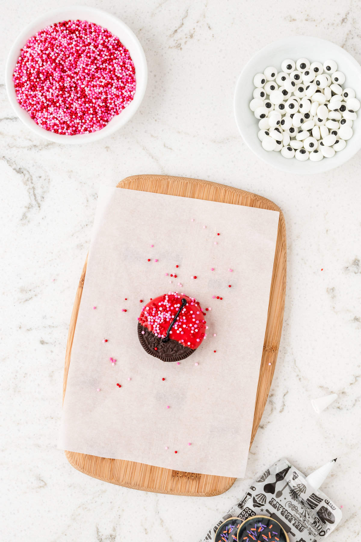 Adding a thin black line down the middle of the dipped oreo with black cookie icing for Ladybug Oreos