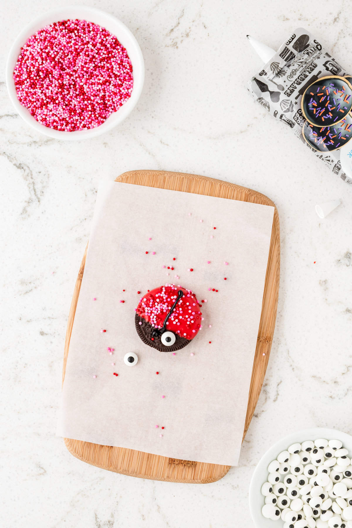 Adding candy eye balls to Ladybug Oreos cookie