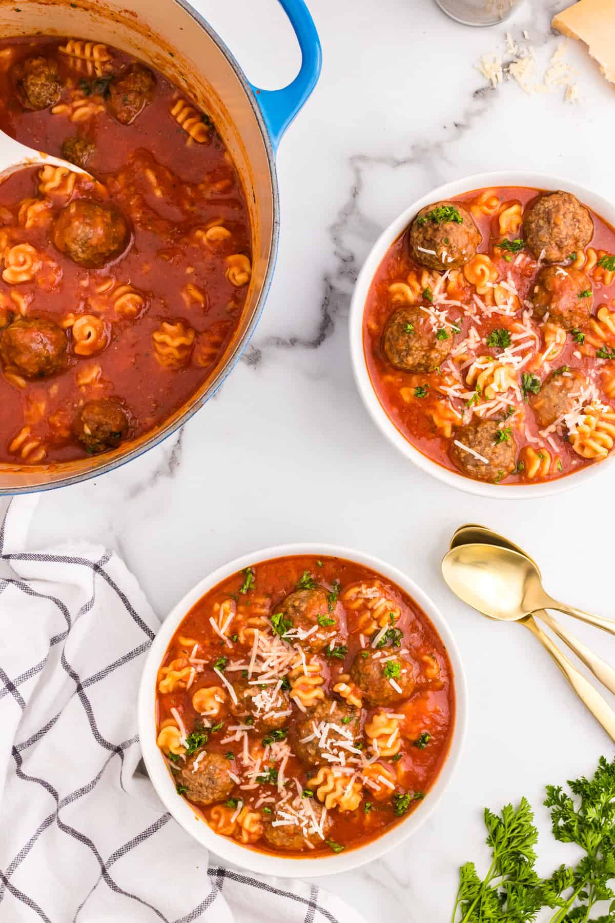 Italian Meatball Soup in bowls topped with fresh parsley and shredded cheese