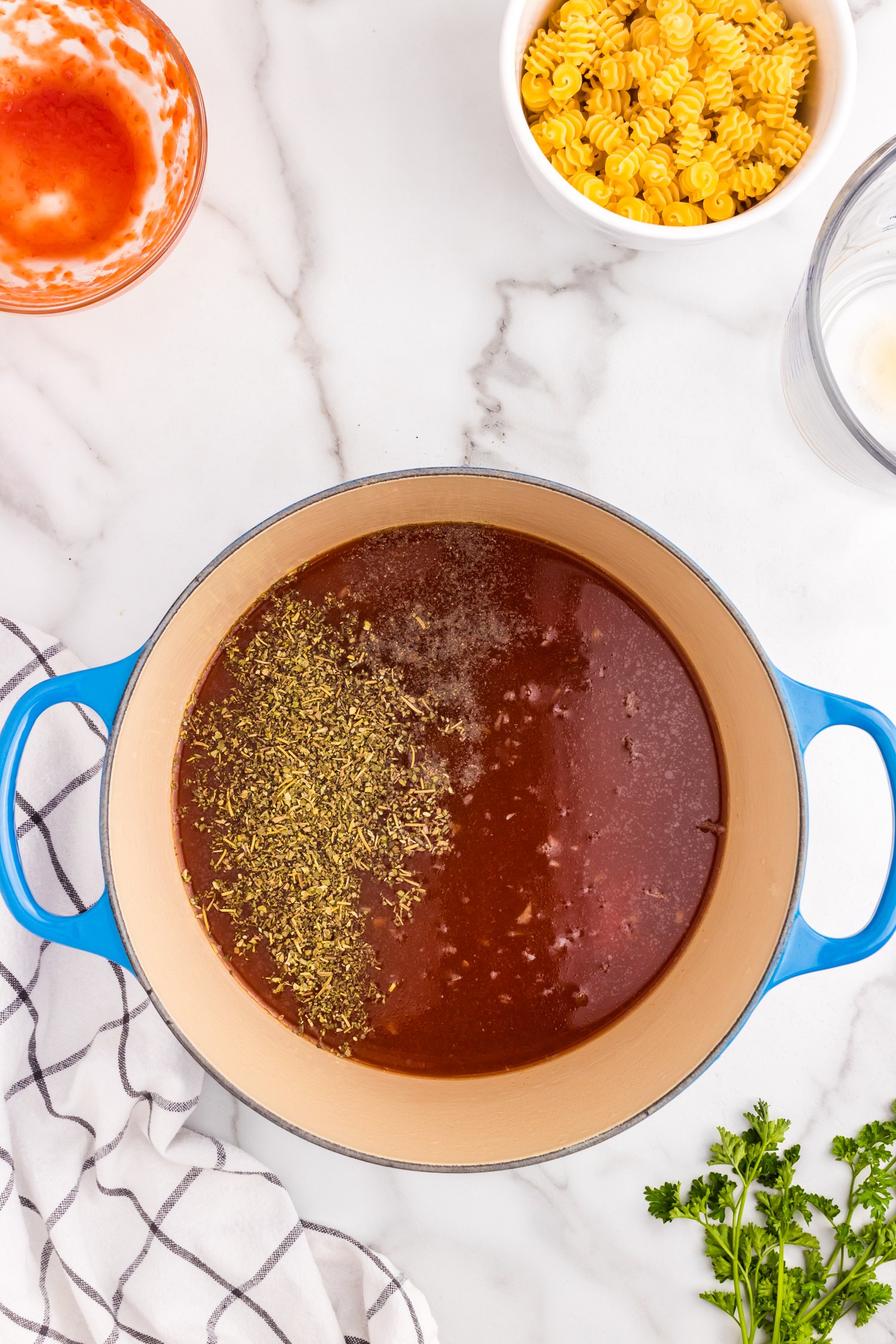 Adding in beef broth and seasoning to stock pot for Meatball Soup