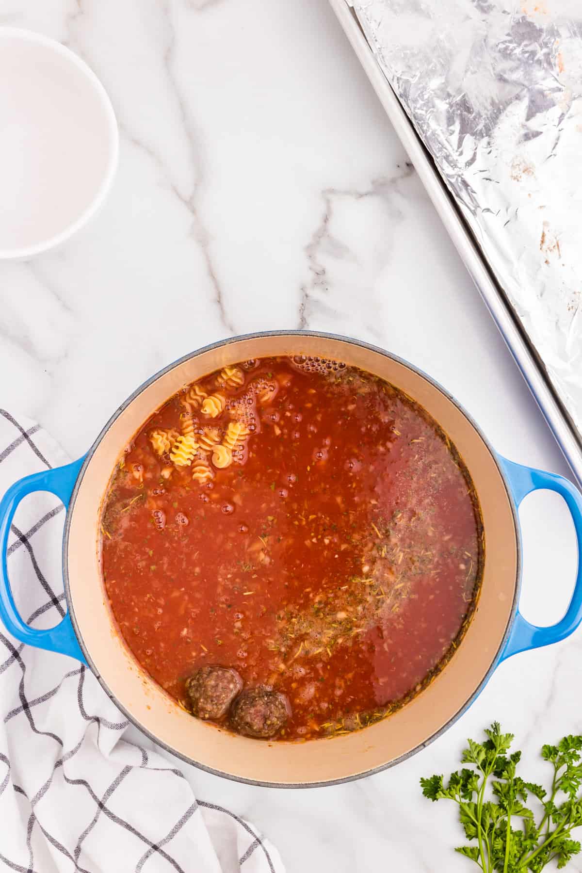 Adding in additional ingredients and cooked meatballs to soup mixture for Meatball Soup recipe