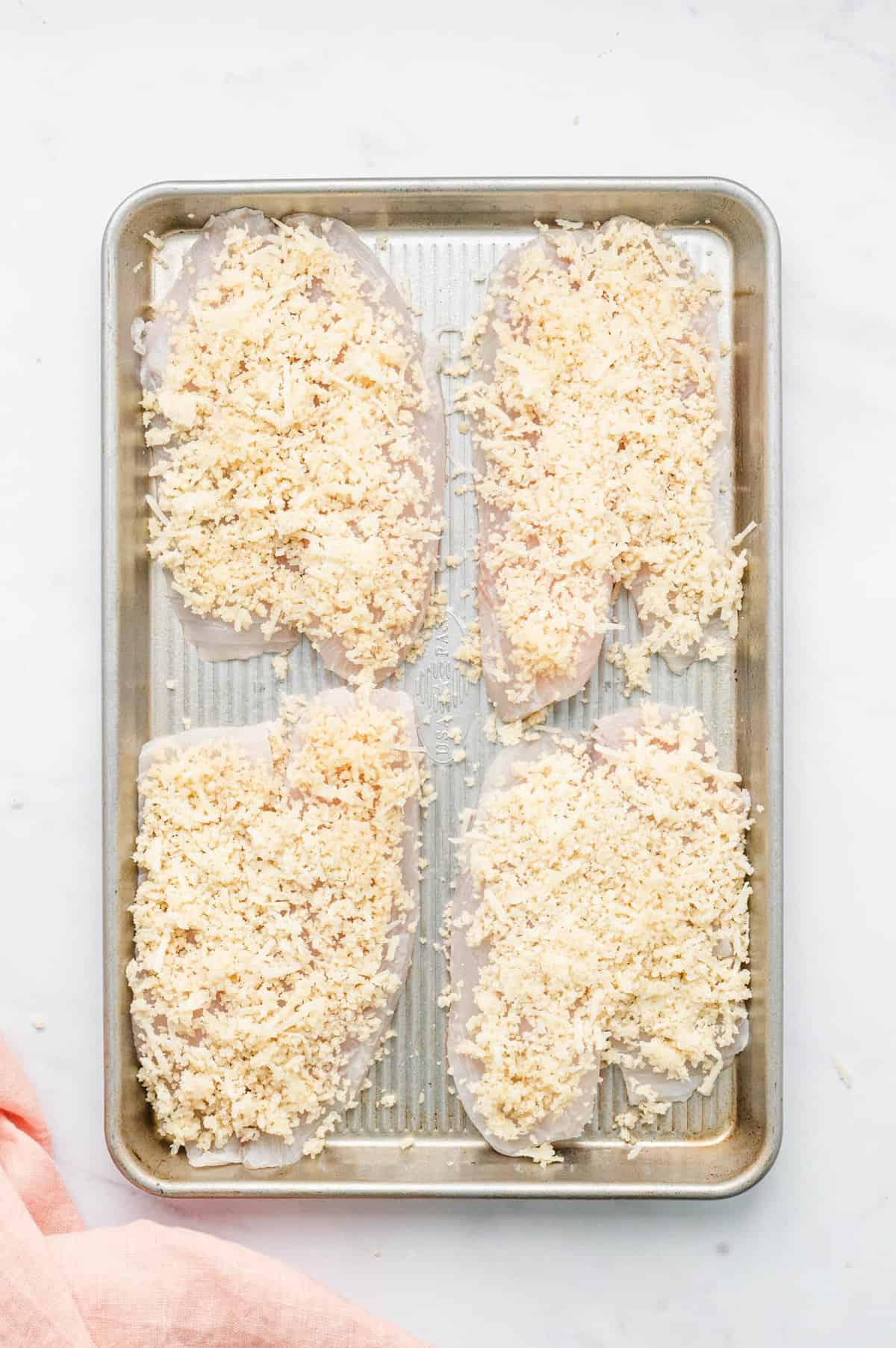 Coating tilapia filets with parmesan mixture on baking sheet for Parmesan Crusted Tilapia recipe