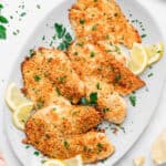 Parmesan Crusted Tilapia arranged on serving plate with lemon wedges