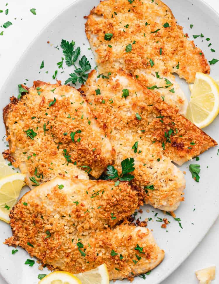 Parmesan Crusted Tilapia arranged on serving plate with lemon wedges