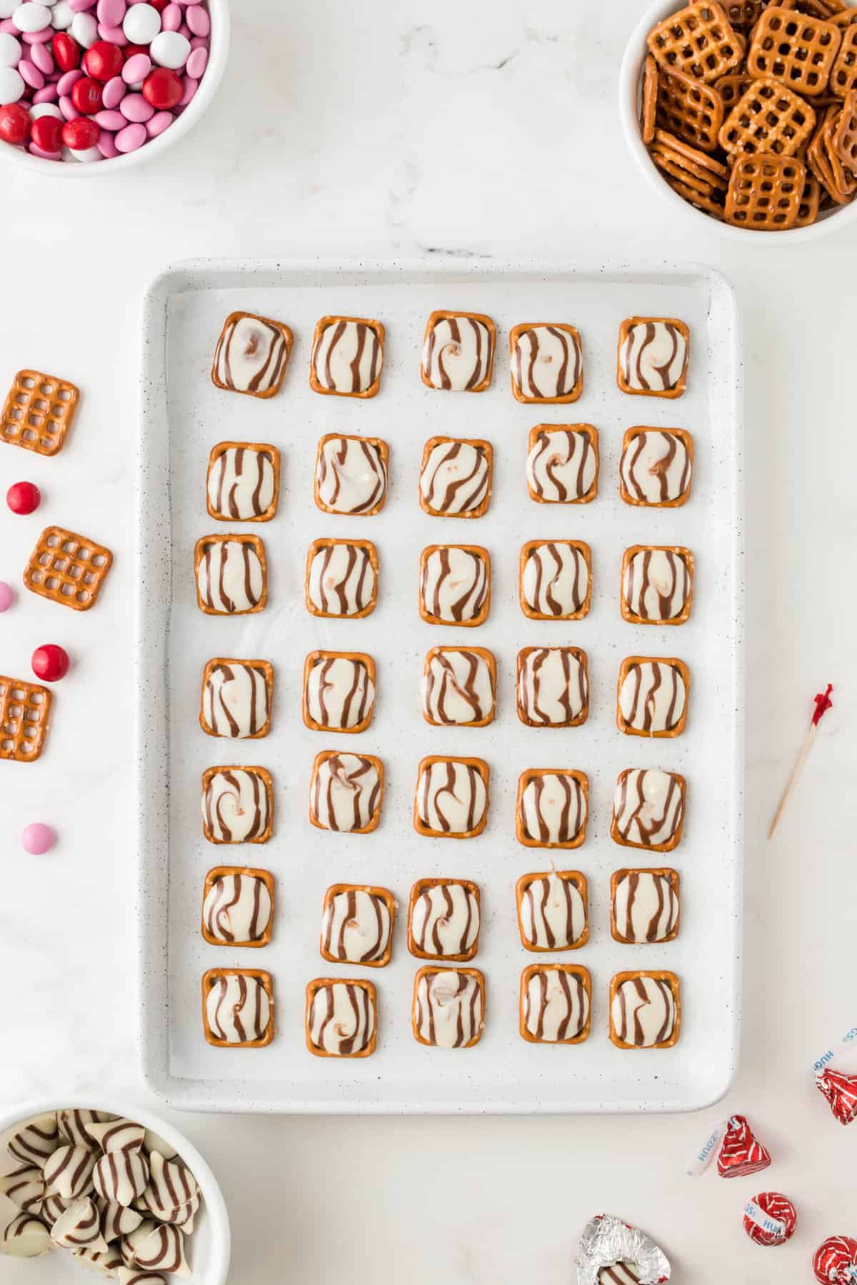 Put the baking sheet in the oven for 3 min 30 seconds or until the hugs are just melted. Remove from the oven and use a toothpick to spread the hug atop of the pretzel.