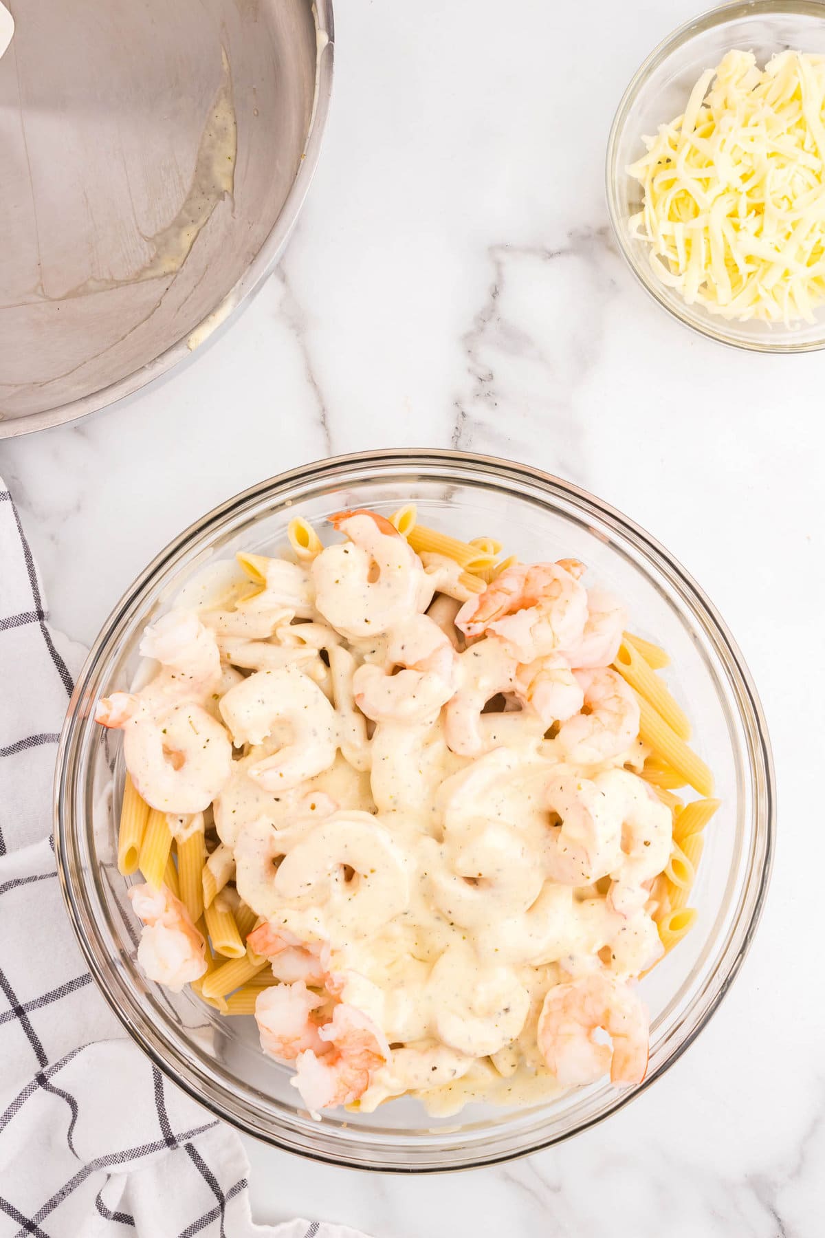 Tossing alfredo sauce, shrimp and penne noodles in mixing bowl for Shrimp Alfredo Casserole