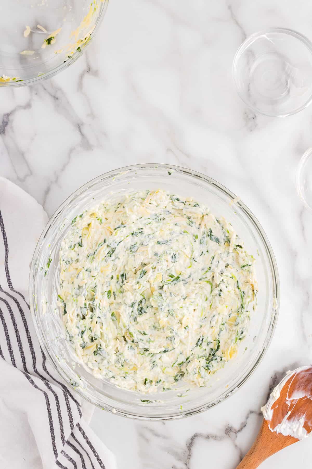 Folded together Spinach Artichoke Dip ingredients in mixing bowl